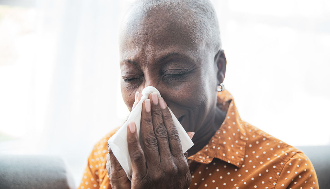 Senior Black woman holding a tissue, wiping her nose